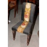 A Victorian nursing chair, the back and seat upholstered in black with central floral tapestry panel