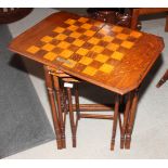 A nest of three oak occasional tables, the top with fold-over chess board, on turned and stretchered
