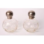 A pair of engraved cut glass grenade scent bottles with spherical silver tops