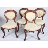 A set of four Victorian walnut dining chairs with oval scroll carved backs inset floral print