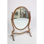 An Edwardian mahogany framed oval swing frame toilet mirror on skeleton stand, 15 1/2" wide