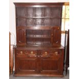 An oak dresser, the boarded back fitted two cupboards over drawers and cupboards to base,