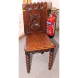 A 19th Century carved oak hall chair with panel seat and back