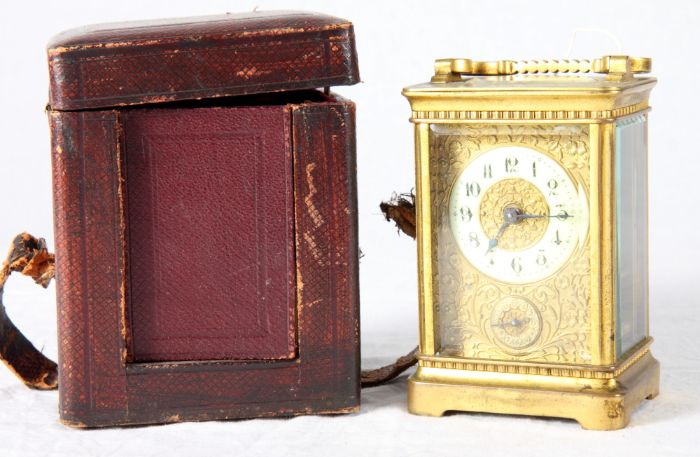 A carriage clock in brass case with floral embossed gilt metal face, subsidiary alarm dial,