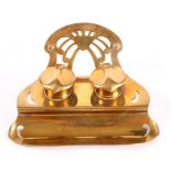 An Art Nouveau brass inkstand, fitted two ink wells and pen rest, 7" wide