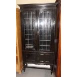 An oak display cabinet enclosed panel doors with oval leaded lights, 36" wide