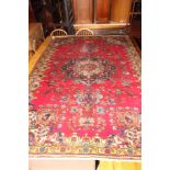 A Persian Tabriz rug decorated central floral medallion on a red ground, 94" x 65" approx