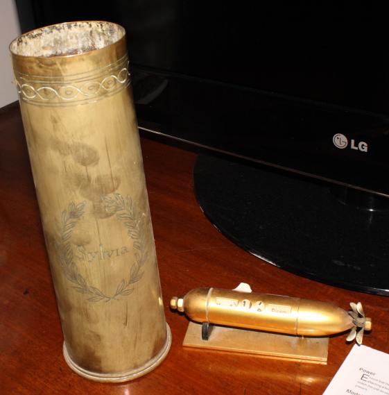 A brass trench art shell case engraved "Northumberland Volunteers" and a brass torpedo desk