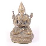 A Tibetan brass figure of a seated Sage, 7" high