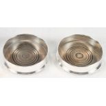 A pair of plain silver bottle coasters with turned wooden bases