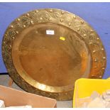 An early 20th Century circular brass tray with planished centre and embossed floral meander to