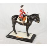 A Coalport china figure, "Trooping the Colour", on ebonised base (riding crop restored)