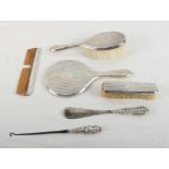 A silver dressing table set comprising a mirror, two brushes, a comb, a shoehorn and a button hook