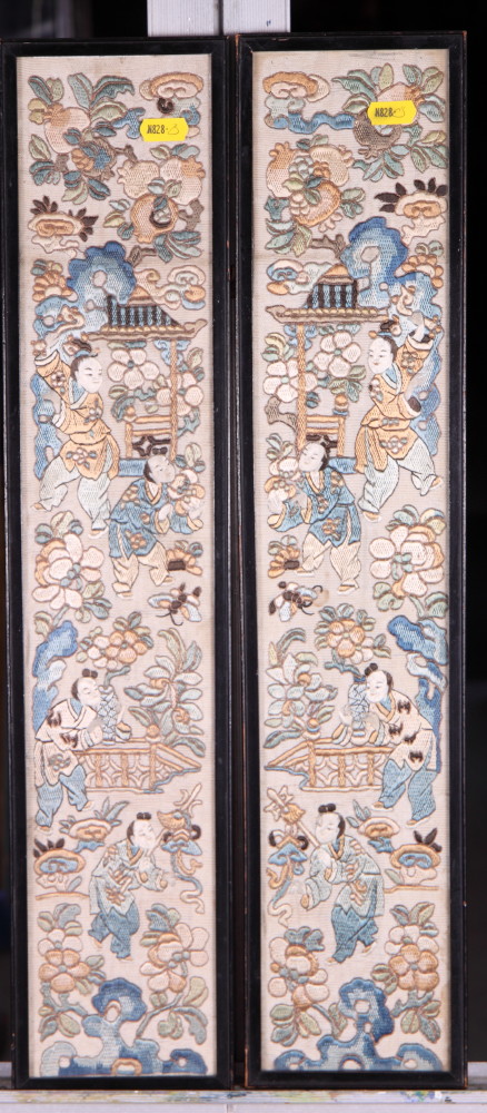 A pair of Chinese framed sleeve panels, embroidered figures amongst flowers, 22" x 4"