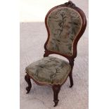 A late Victorian carved mahogany showframe low seat nursing chair, upholstered in a jazz fabric,