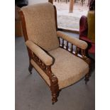 A Victorian oak framed armchair with spindle decorated arms, upholstered in a brown patterned