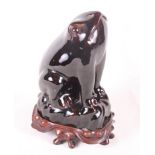 A Chinese monochrome treacle glazed model toad, 9 1/2" high, on carved rosewood stand