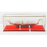 A scale model of the Thai Royal Barge with figures and oarsmen, 23" long, in glass case