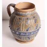 A Royal Doulton stoneware jug decorated in blue, brown and green glazes with panels of wrythen and