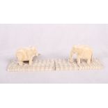 A pair of carved ivory elephants mounted on polished elephant molar bases, 5 1/2" long