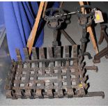 A wrought iron fire grate, a pair of andirons with basket finials and a cast iron fireback decorated