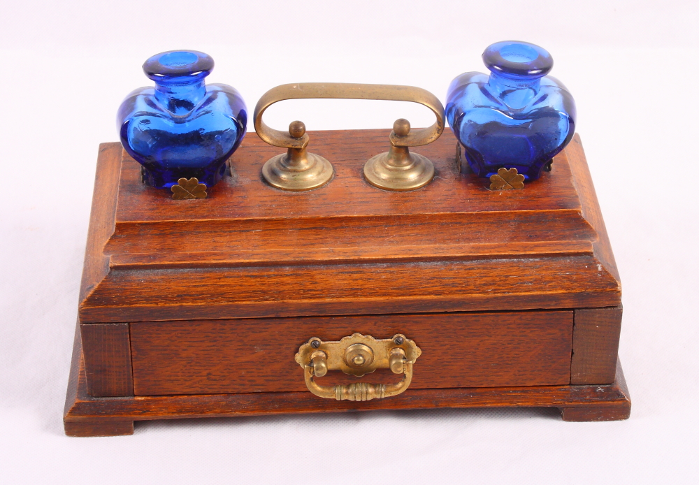 An early 20th Century oak desk inkstand, fitted lower drawer and two heart-shaped blue glass ink