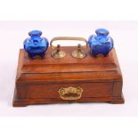 An early 20th Century oak desk inkstand, fitted lower drawer and two heart-shaped blue glass ink