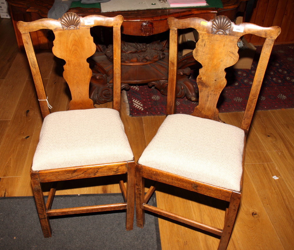 A set of four provincial oak standard dining chairs of Georgian design with shell carved splats