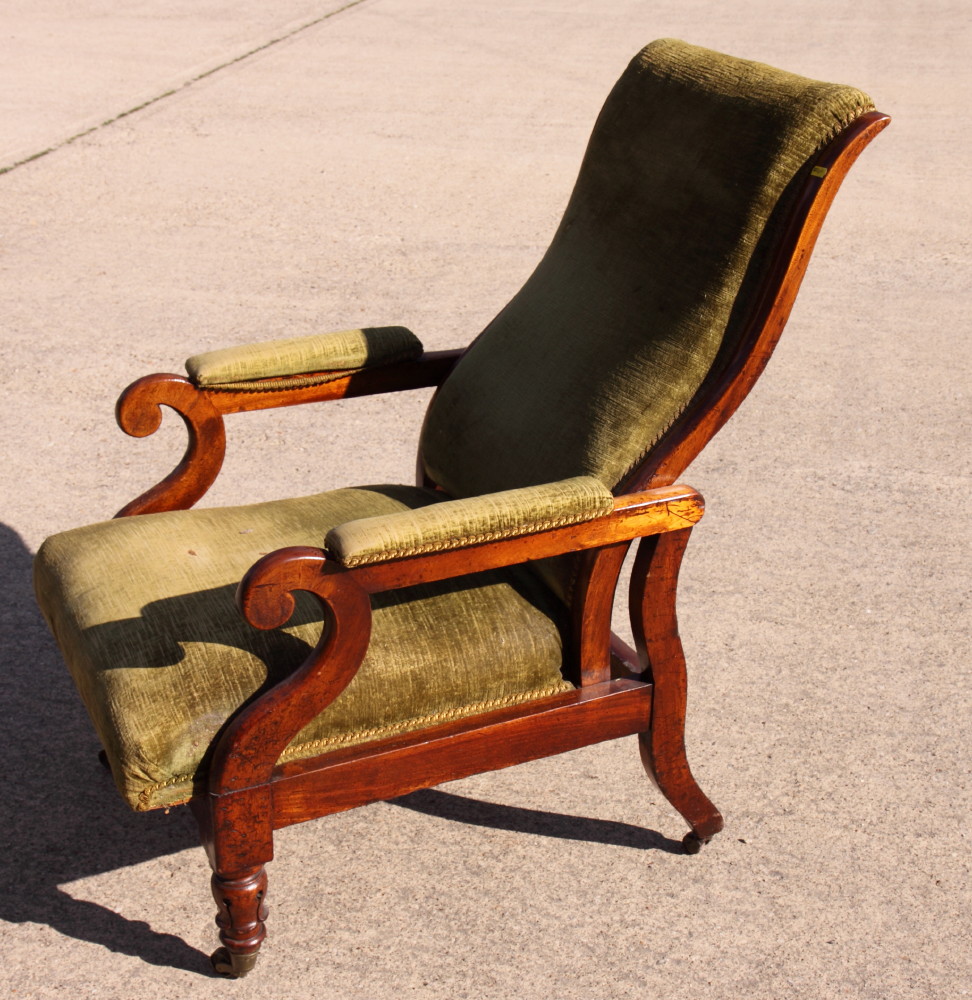 A Victorian mahogany framed recliner armchair with scroll carved arm terminals, upholstered in a