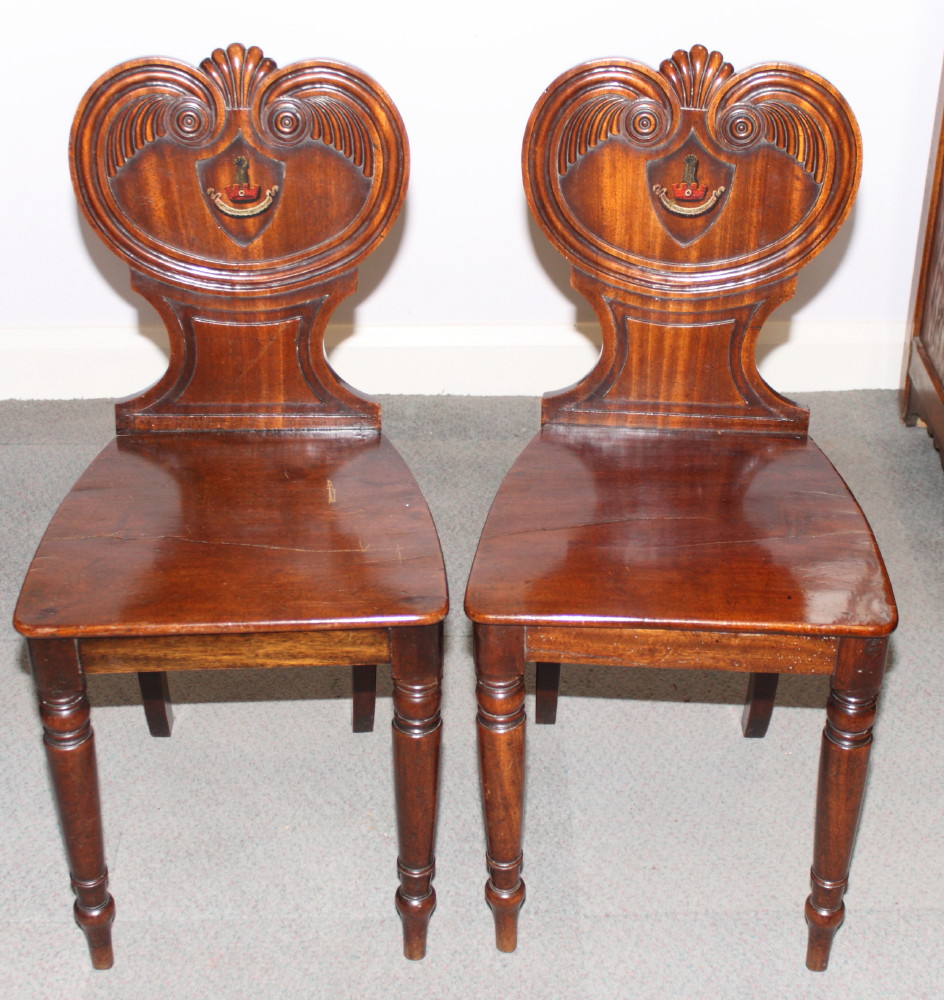 A pair of Victorian mahogany hall chairs with carved backs inset painted armorial of the Clayton