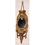 A pair of 19th Century ornate gilt wood wall shelves with oval mirror panels with swag, shell and