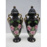 A pair of Edwardian style black glazed twin gilt handled urns, decorated with roses, each 36cm