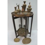 A round copper tray on a folding stand,