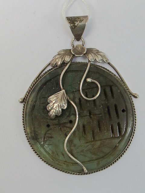 A hardstone and silver disc pendant. Gre