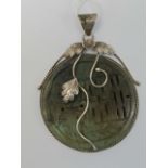 A hardstone and silver disc pendant. Gre