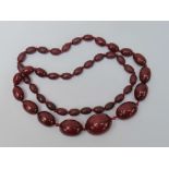 A row of graduated cherry amber beads. L