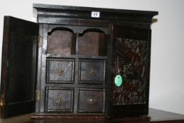 AN ANTIQUE OAK TABLE CABINET WITH CARVED DOORS