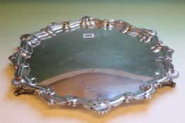 A SILVER SALVER WITH C-SCROLL AND SCALLOP RIM ON SPLAYED FEET. SHEFFIELD 1915 45cms DIAMETER. 67ozs