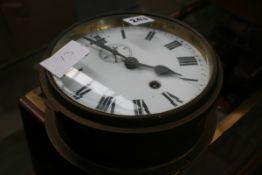 A SMALL BRASS CASED BULKHEAD CLOCK WITH ENAMELLED DIAL AND SUBSIDARY SECONDS