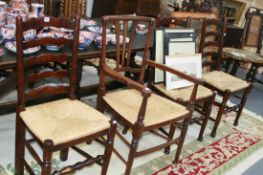 A SET OF FOUR RUSH SEAT LADDER BACK CHAIRS AND A SIMILAR ARMCHAIR