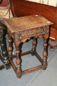 AN ANTIQUE OAK JOINT STOOL WITH RISING LID AND CARVED FRIEZE