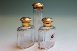 THREE SILVER GILT TOPPED FACETED GLASS TOILET JARS, LONDON 1897.   £100-150