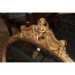 A LARGE EDWARDIAN GILT FRAMED MIRROR WITH CARVED CHERUB CREST