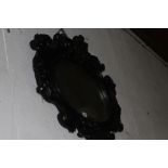 A SMALL OVAL WALL MIRROR WITH ELABORATE DEEP CARVED FRAME