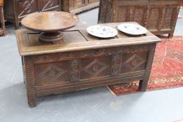 An early carved oak coffer with panelled lid above carved triple panel front, 137cm wide