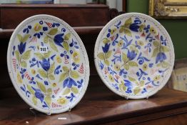 A pair of 19th Century tin glaze plates, decorated with blue, yellow and pink designs, 31cm