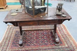 A carved rosewood William IV library table with two apron drawers, trestle form supports on bun