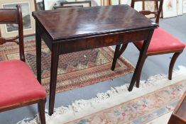 A late 18th Century mahogany fold over tea table, the moulded edge top over inlaid frieze, on fluted