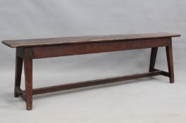An 18th Century oak form, with plank top over peg jointed square tapered legs united by stretcher,