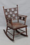 An Arts and Crafts oak and embossed leather rocking chair, the back and arms with square panel